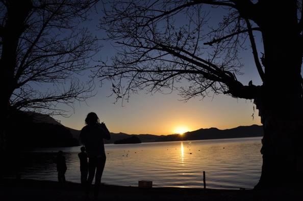瀘沽湖的夕陽西下、寧靜的湖面鑲著枯樹的湖邊，陳伯伯將此美景記錄下來。（拍攝於110/04/28）