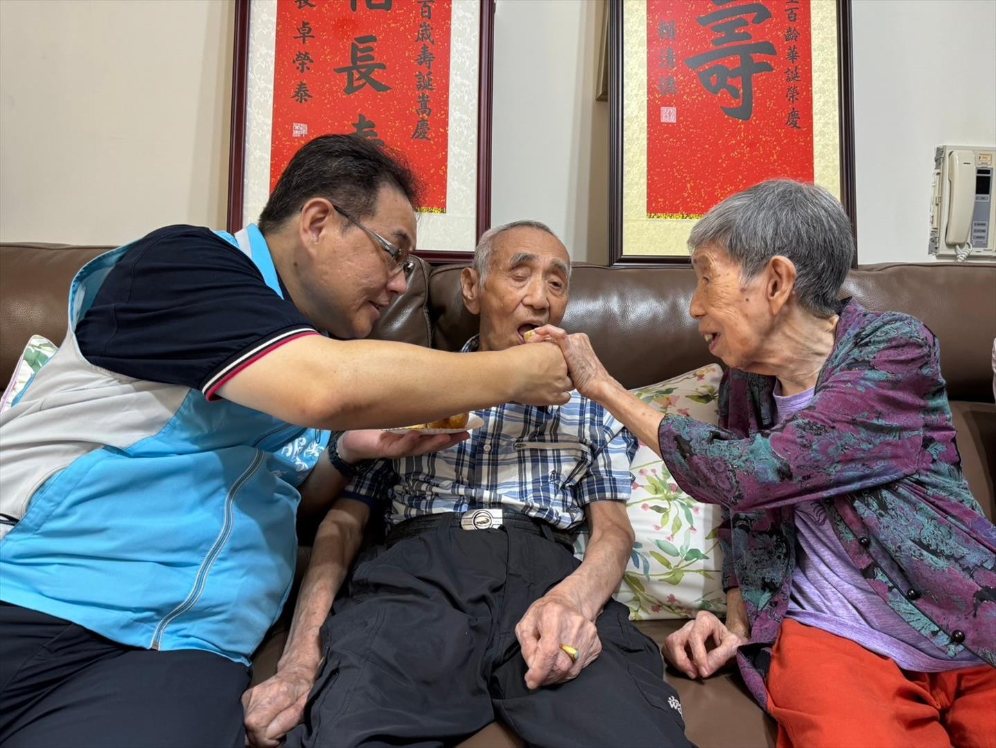 鞠處長（左一）與胡媽媽一同親餵百歲榮民胡伯伯吃生日蛋糕