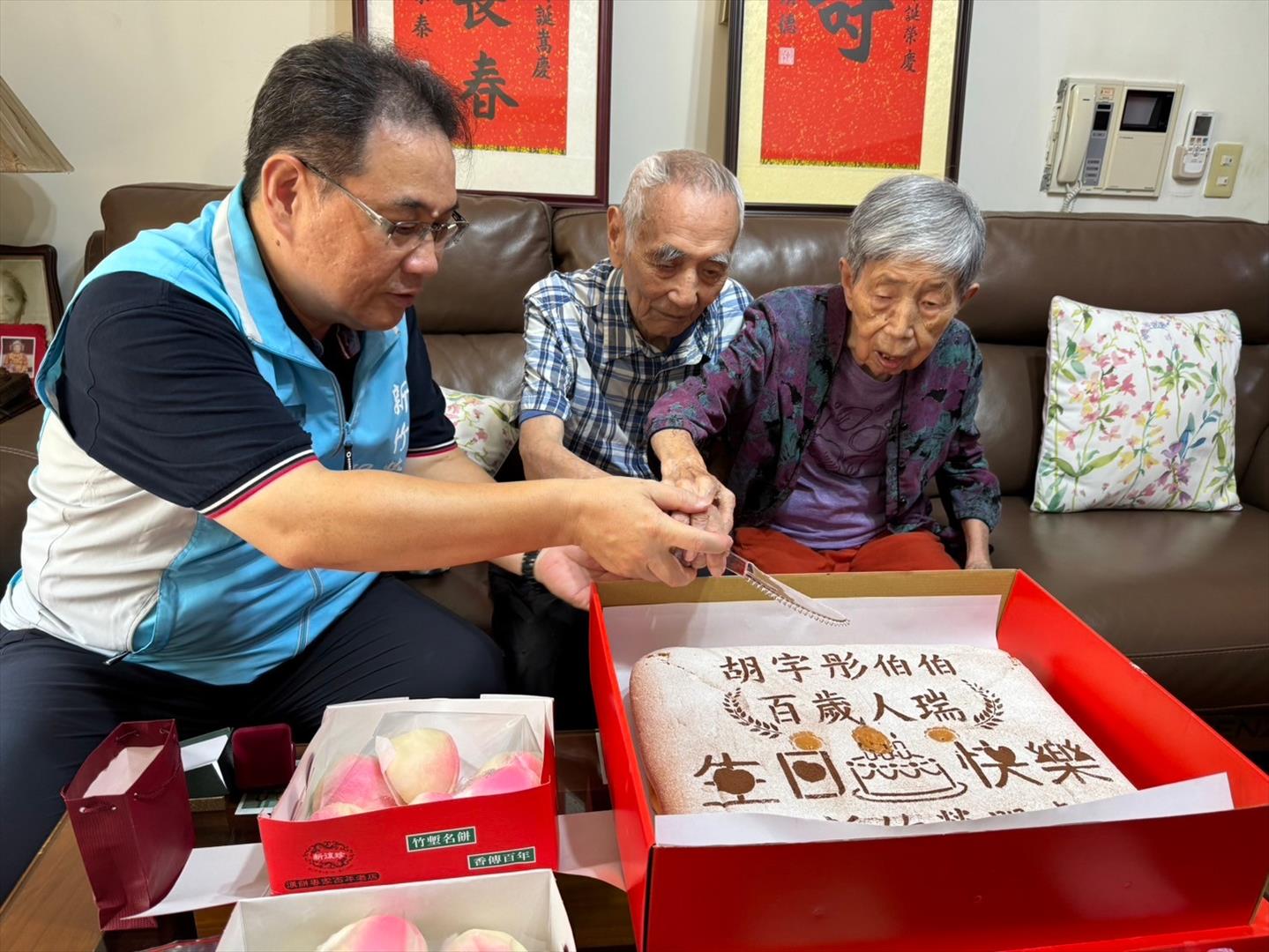 鞠處長（左一）與胡媽媽為百歲榮民胡爺爺切生日蛋糕